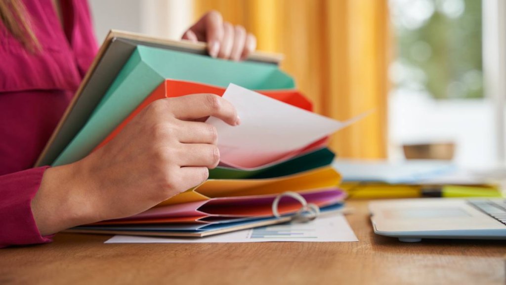 Work from home insurance jobs: Close-up of unrecognizable woman's hands working or studying from home and keeping her documents in a colorful filing cabinet. Concept of businesswoman, entrepreneur, freelancer and student.