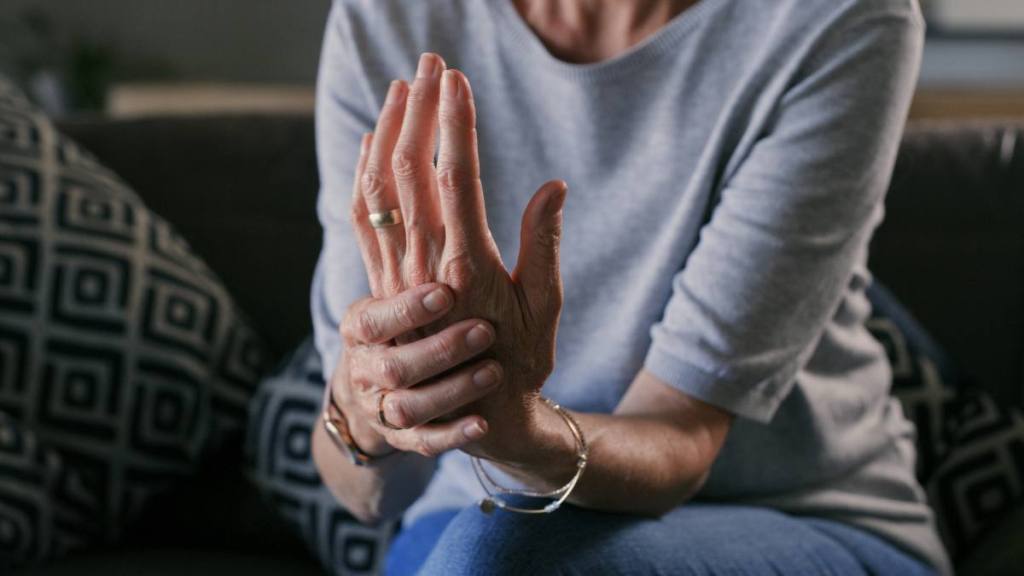 a close up of a woman holding her hand with joint pain, which can benefit from garlic and honey