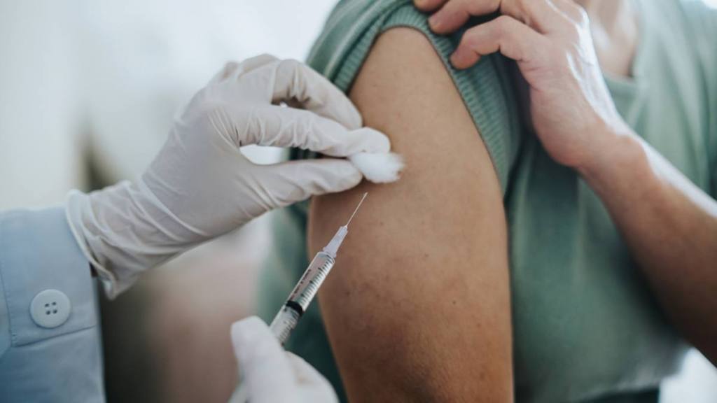How to prevent a cold when you feel it coming: Close up of senior Asian woman getting Covid-19 vaccine in arm for Coronavirus immunization