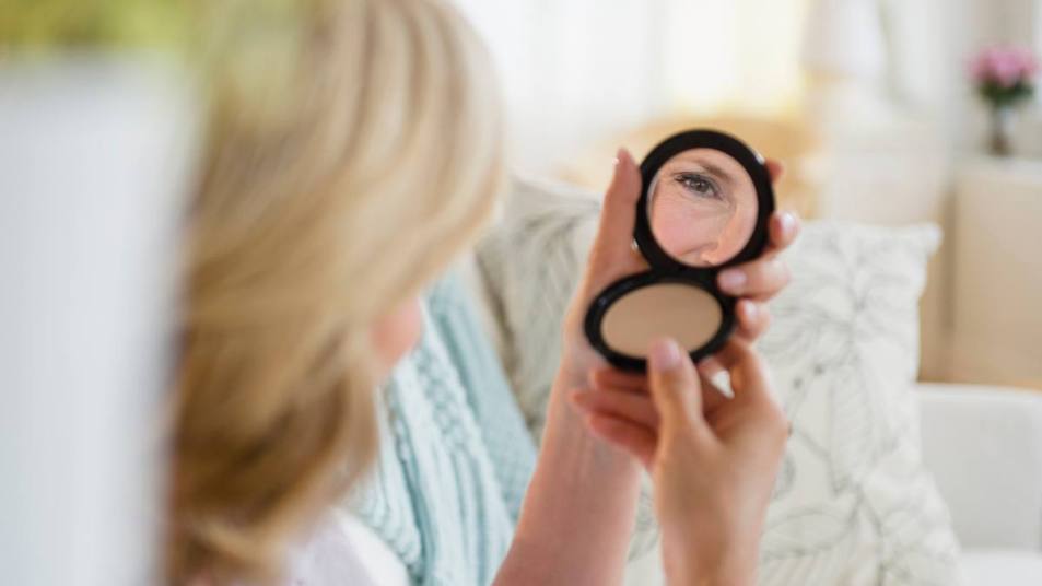 How to Fix Broken Makeup: Caucasian woman admiring herself in mirror