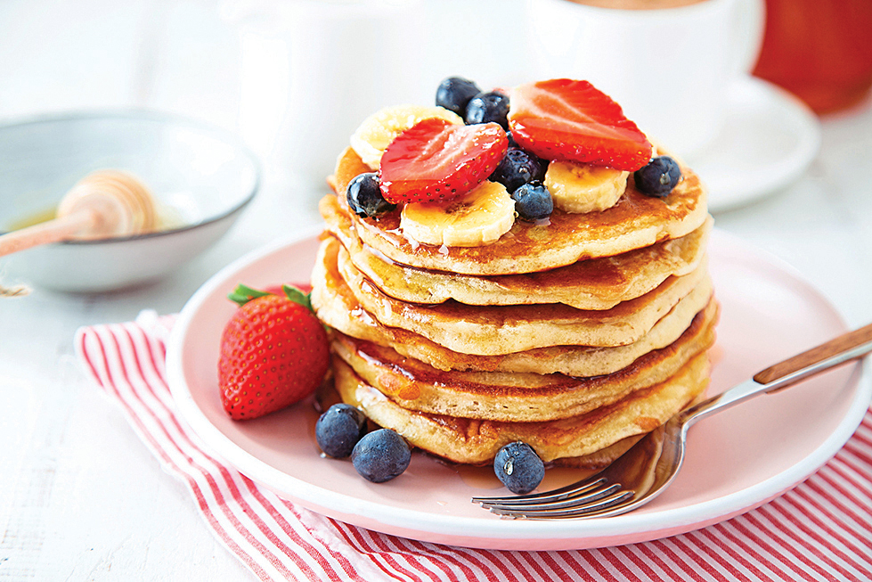 Winter brunch ideas: stack of pancakes on tabletop topped with fruit