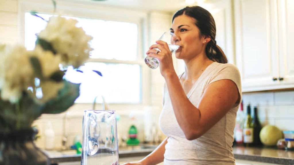 How to prevent a cold when you feel it coming: Beautiful Young Adult Millennial Female using water in residential home