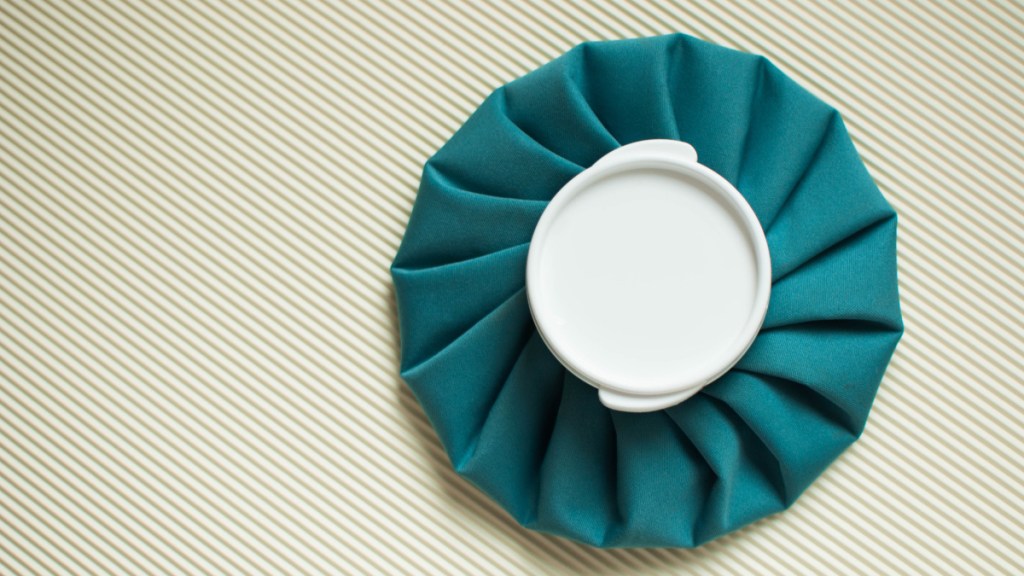A teal ice pack with white lid on a striped background used to ease a migraine