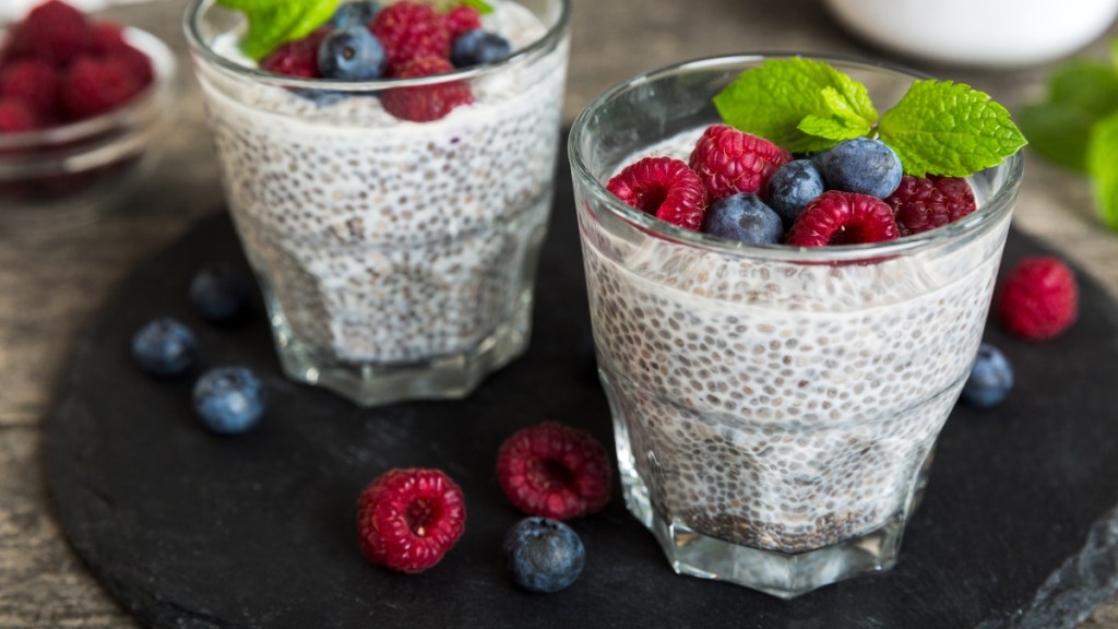 A cup of chia pudding topped with blueberries, raspberries, and mint, which can help with IBD vs IBS
