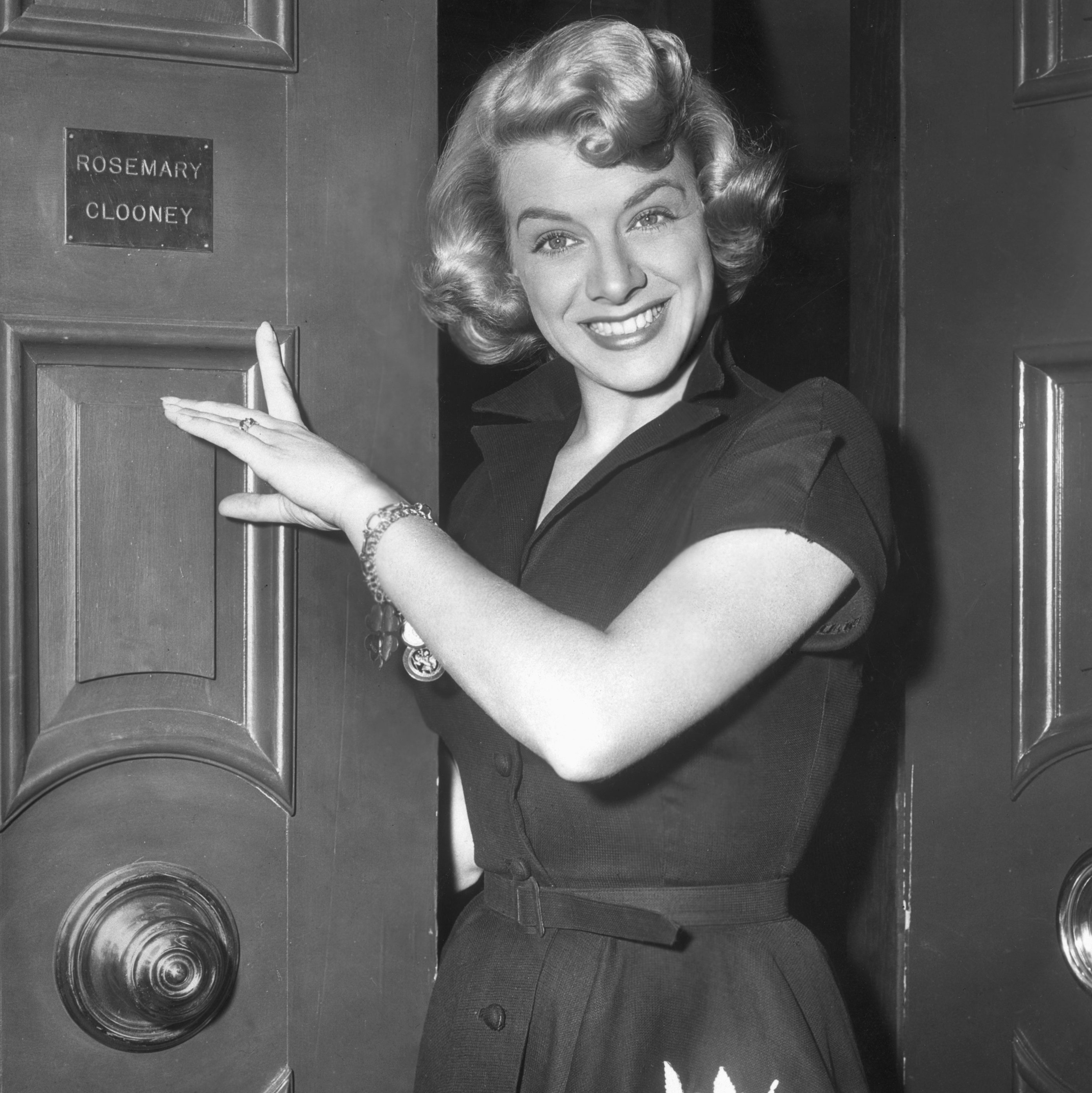 Rosemary Clooney points to her nameplate on a door, 1945