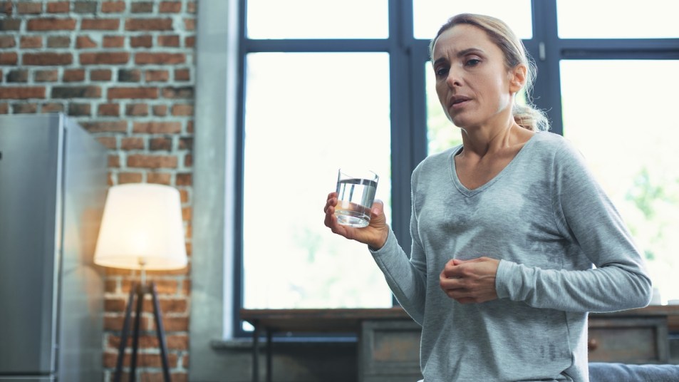 Woman sweating and holding glass of water