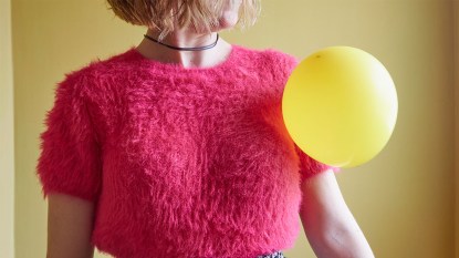 How to remove static from clothes: womans with a balloon clinging to her sweater with static