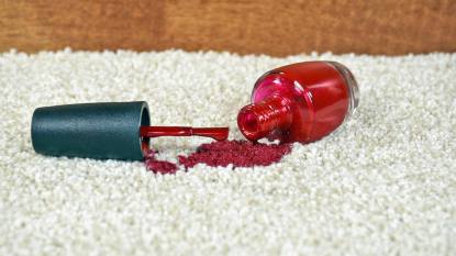 how to remove nail polish from carpet: Close up of bright red nail polish on light colored carpet