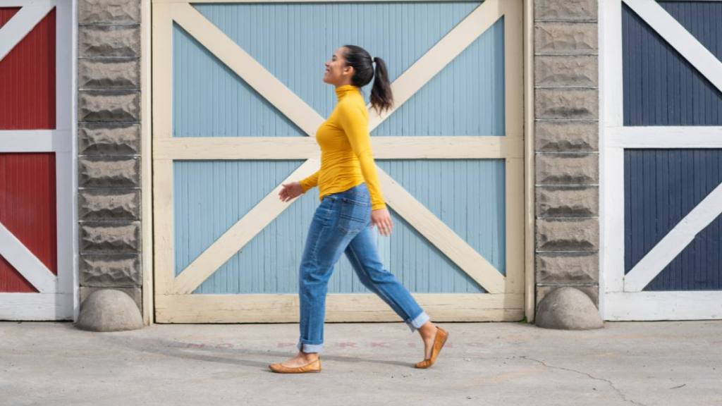 Woman in a yellow shirt walking by colorful doors outside, which helps with knee pain when bending