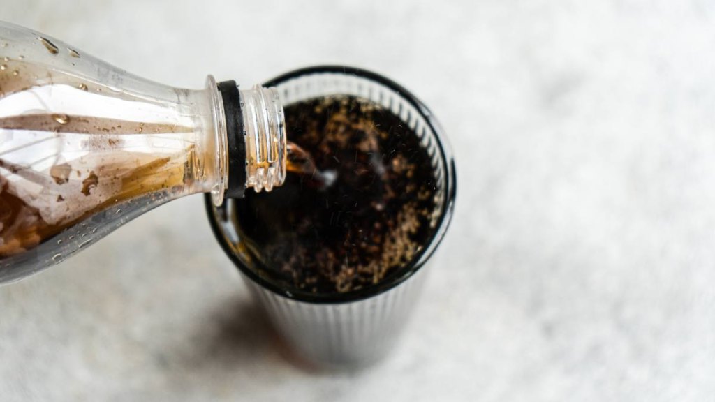 How to clean electric kettle: Overhead view of glass of cola being poured