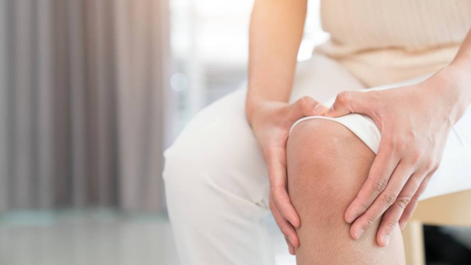 A close up of a woman touching her knee, which has pain when bending