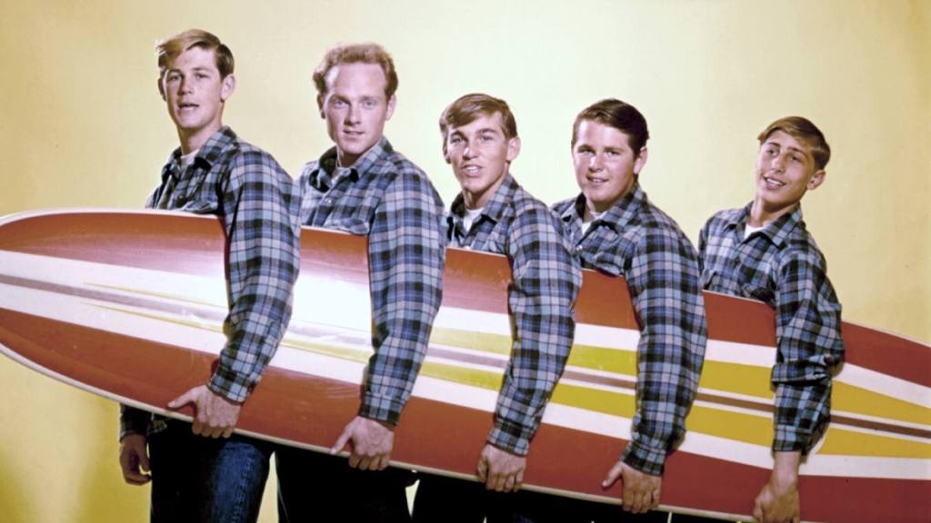 Group of boys hold a surfboard