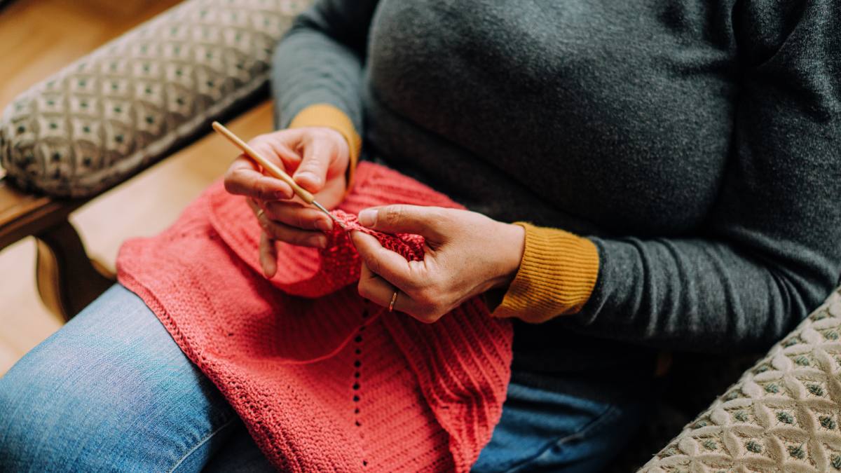 crochet jobs remote: Close-up of hands doing crochet with pink wool viewed from a high angle view