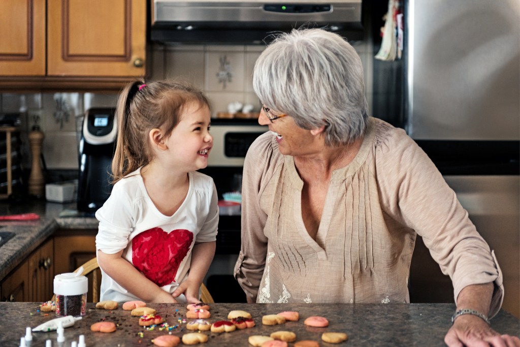 Little girl making valentine’s cookie with grandma