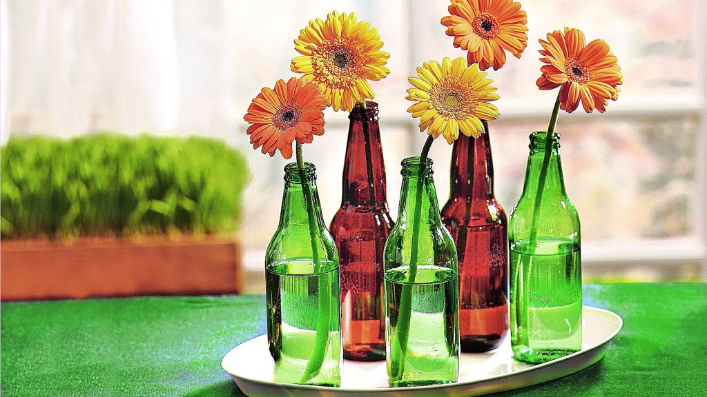 DIY football decorations: Clean green and amber beer bottles filled with water and single gerbera daisies, then displayed in a group on an oval tray 