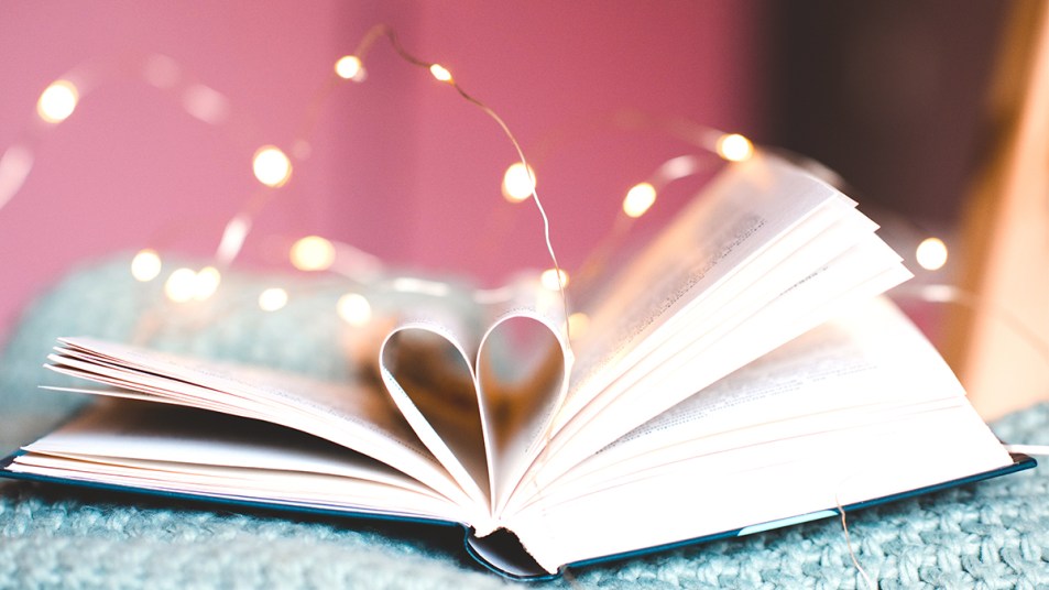 Romance books: feature image of book opened with pages folded into heart on pink background