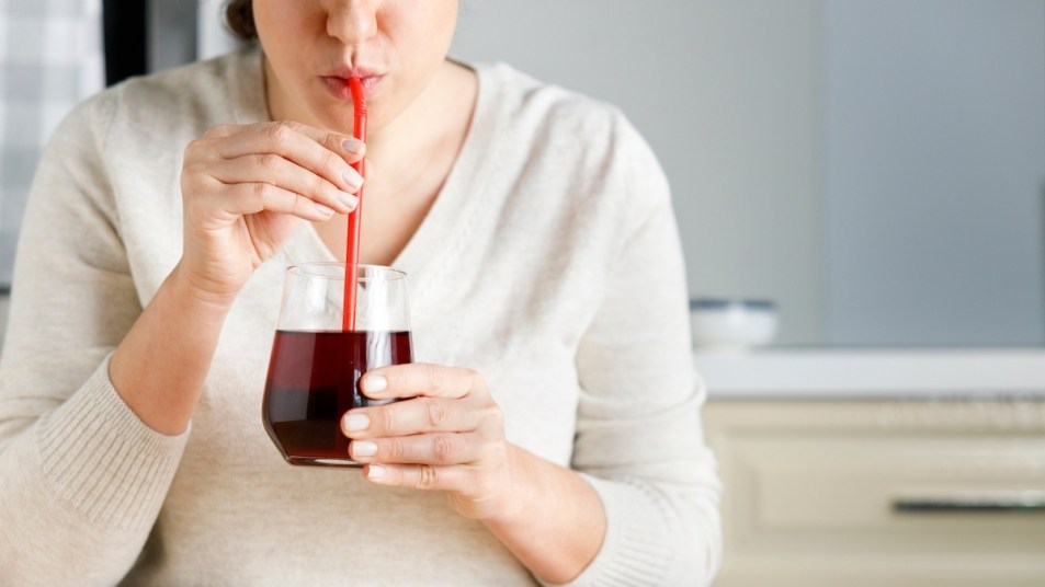 Woman drinking pomegranate juice with straw
