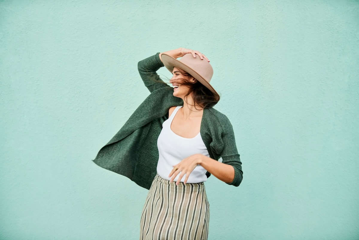 Smiling woman holding her hat in breeze