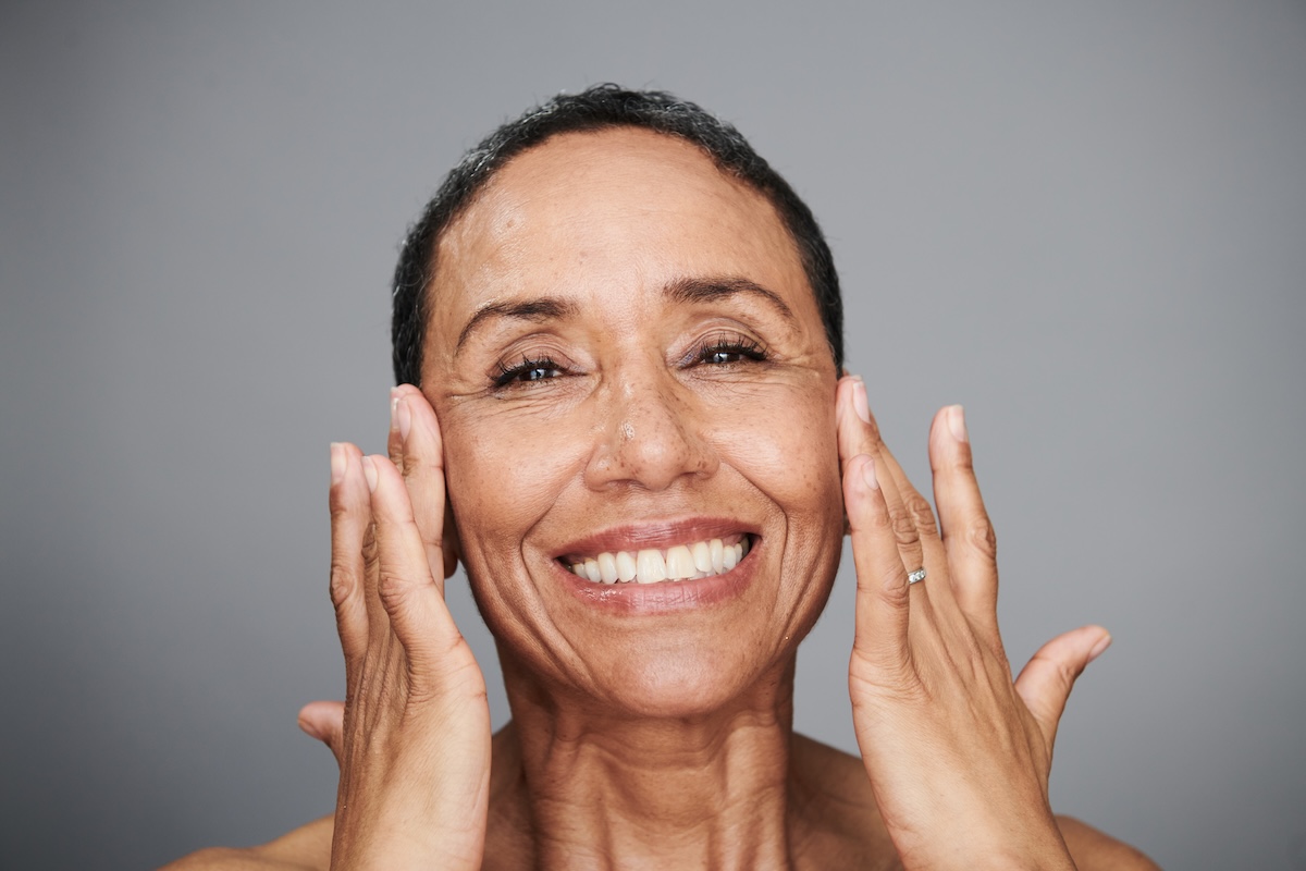 Portrait of a mature woman rubbing skincare on to her face.