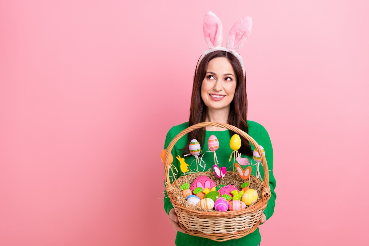 Photo of pretty cheerful person hands hold festive easter basket painted eggs cookies food look empty space isolated on pink color background.