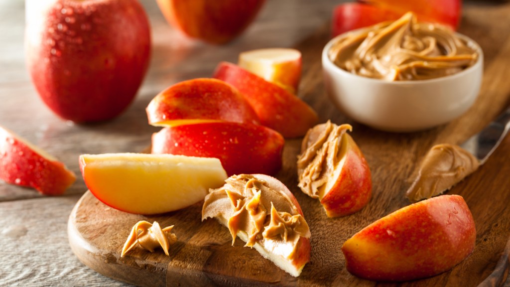 Slices of red apple with peanut butter, which helps you not fall asleep after eating