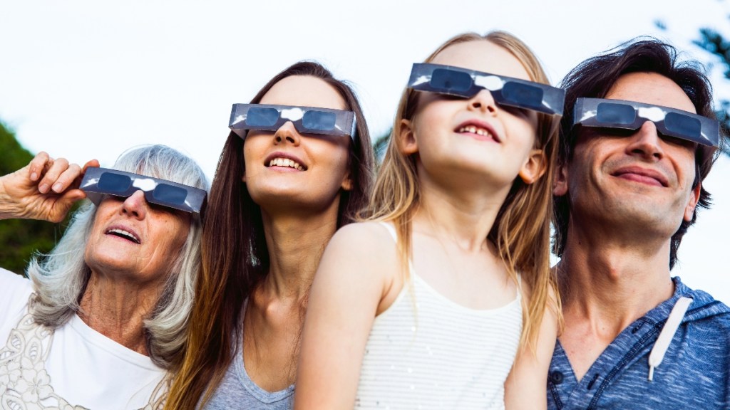 A family watching an eclipse wearing glasses