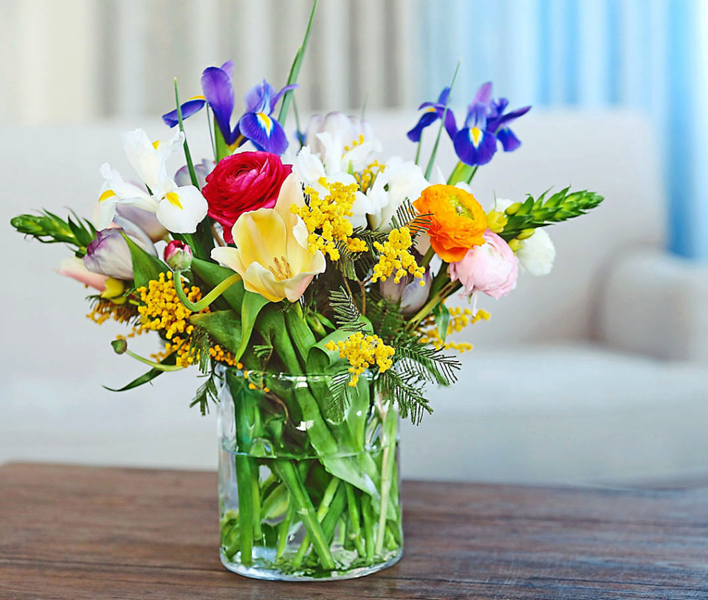 St patrick's day party: rainbow-hued bouquet on tabletop in glass vase