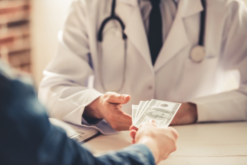 Cropped image of doctor in white coat talking money from his patient