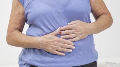 mature woman with leaky gut holding her stomach