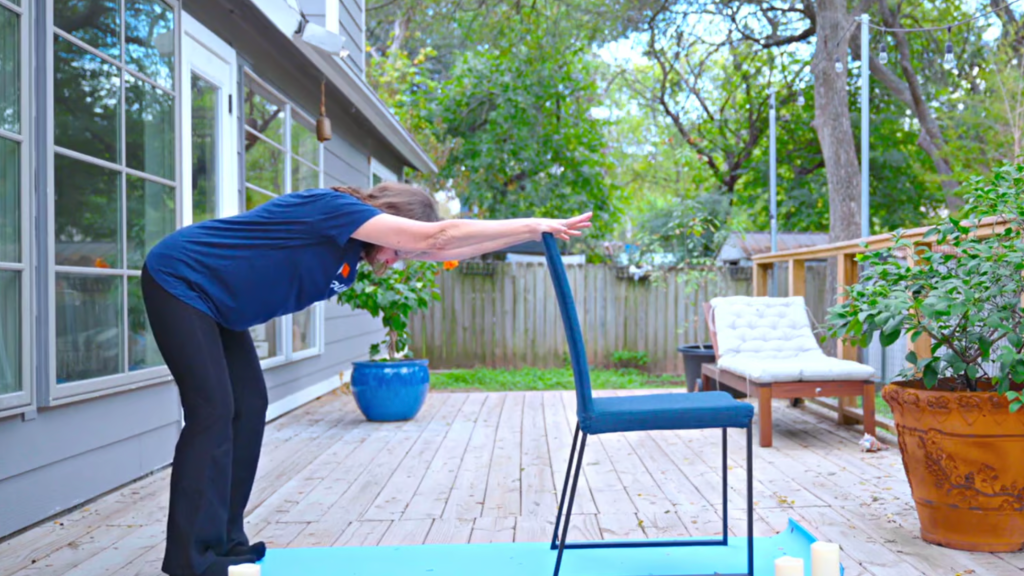 Woman stretching outside using a chair to balance