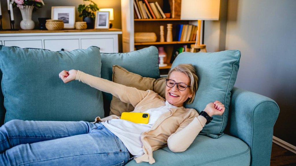Mature woman waking up on the couch after finding out how long should a nap be