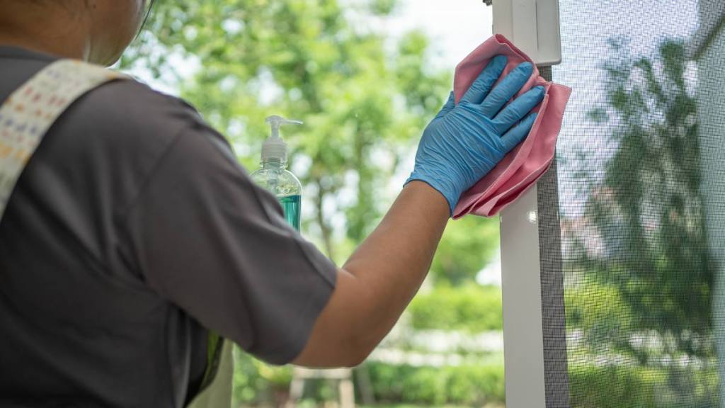how to clean window screens: Maid cleaning wipe and wash the glass at widow in home. -