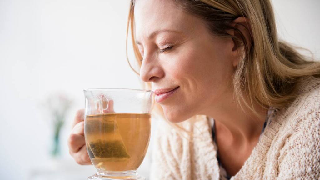 benefits of oregano tea: Caucasian woman smelling cup of tea