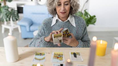 beginner tarot spread: Senior woman reading tarot cards on table at home