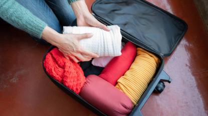 how to roll clothes for packing: Woman open her suitcase for pack and arranging cloths for travelling on holiday period