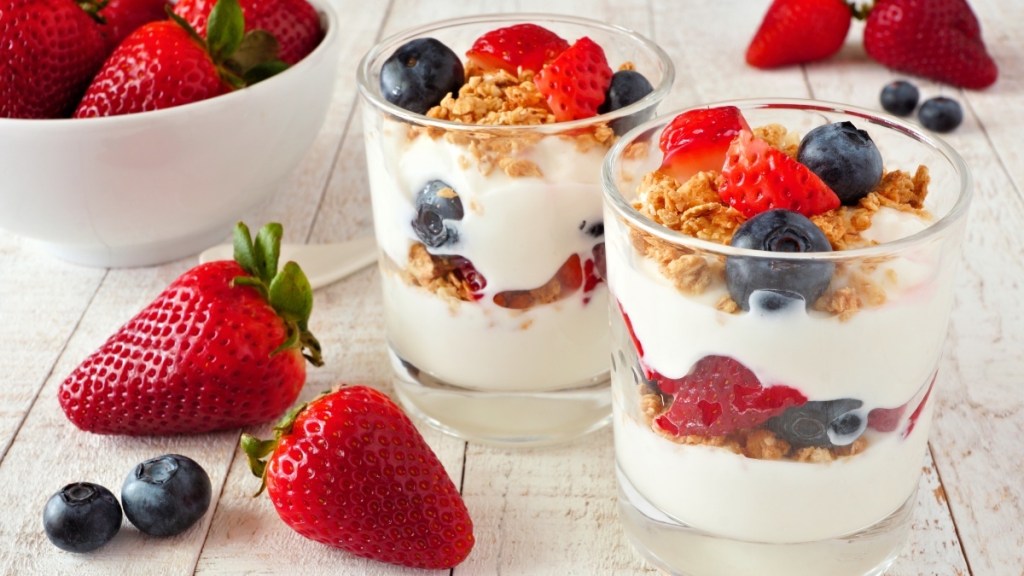 Two glasses of yogurt parfait topped with blueberries and strawberries