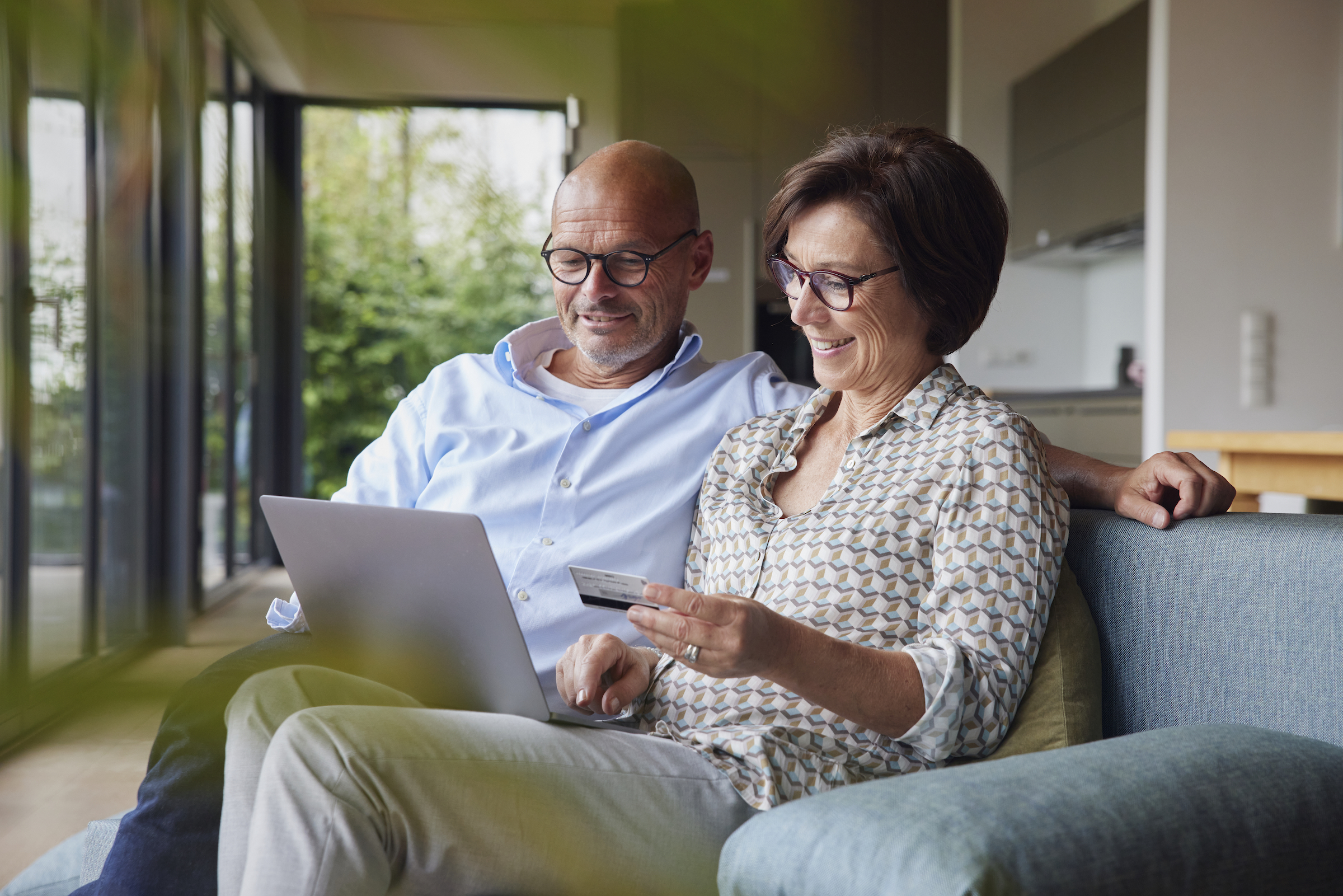 Happy couple making payment through credit card on laptop at home