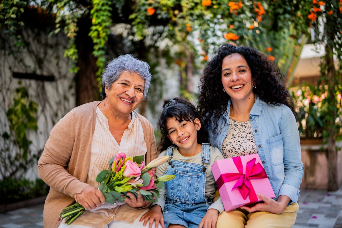 Portrait of granddaughter holding gifts with family outdoors