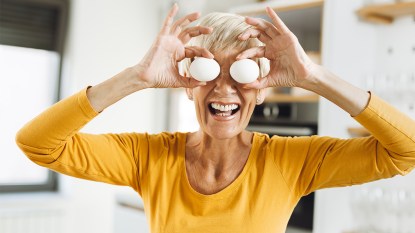 Happy woman covering her eyes with eggs