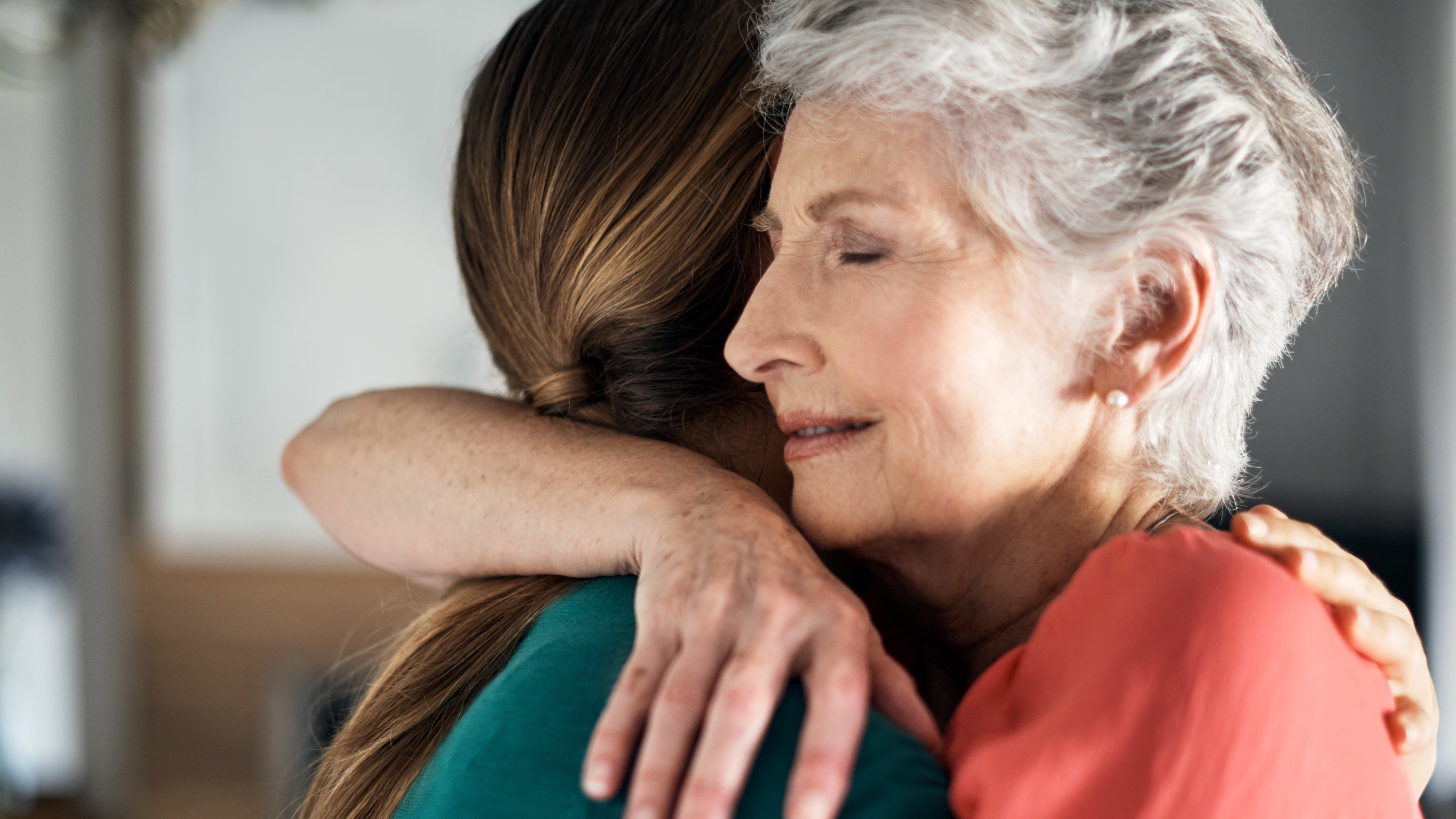 senior woman embraces younger woman, as they support each other in grief