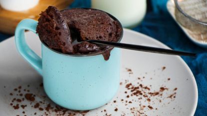 microwave brownie in a blue mug with spoon inside on a white plate