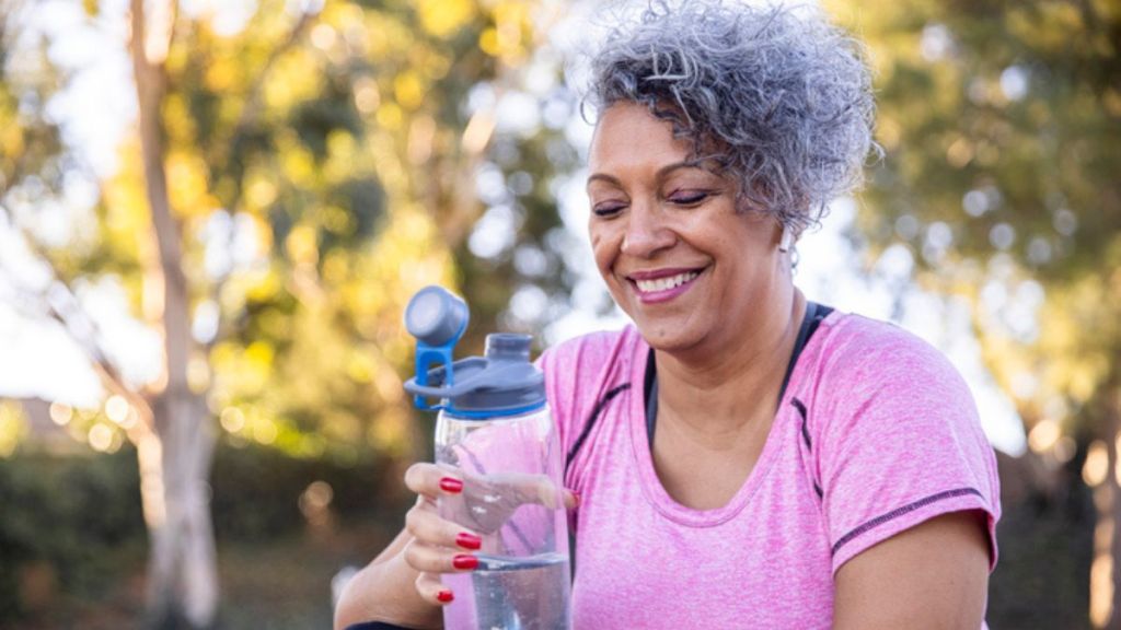 A mature woman drinking water outdoors to start losing weight on semaglutide