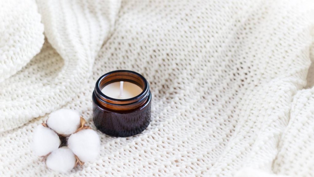 Gifts for Mother's Day: Soy wax candle in amber glass with cotton flower with copy space
