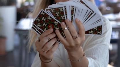 Woman in a light outfit reads Tarot cards on a table in a cafe