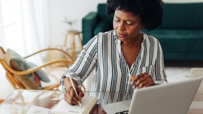 work from home banking jobs: Woman sitting at table and taking notes at home office. African woman working from home.