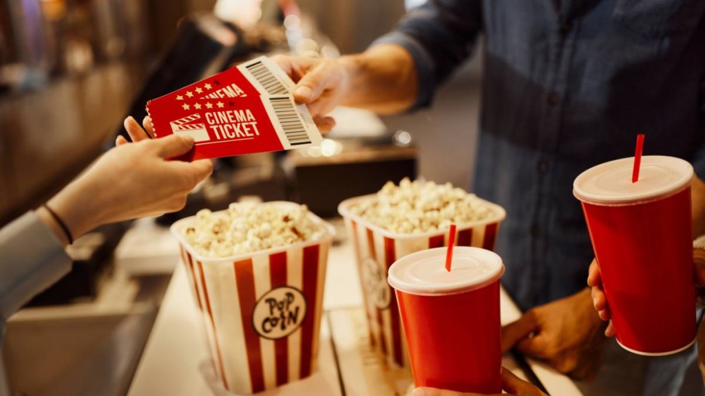 Close up of unrecognizable cashier giving movie tickets to her customer in cinema.