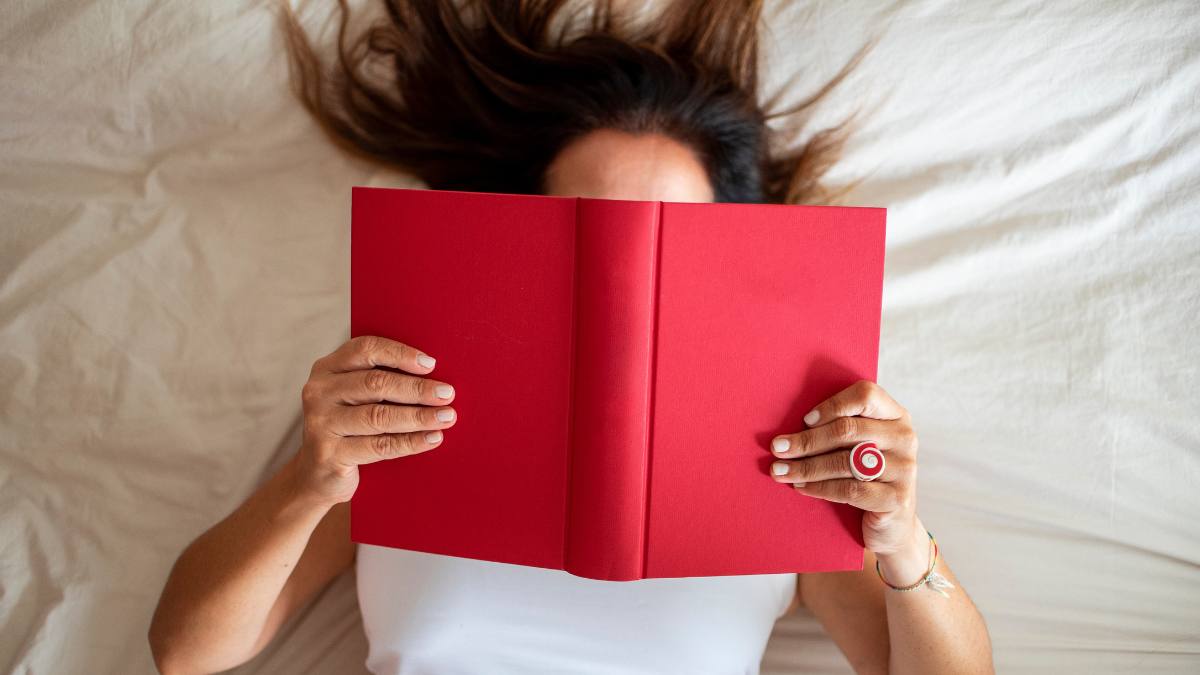 How to remove stickers from books: Woman wake up and read book on bed, relax and happiness in holiday.