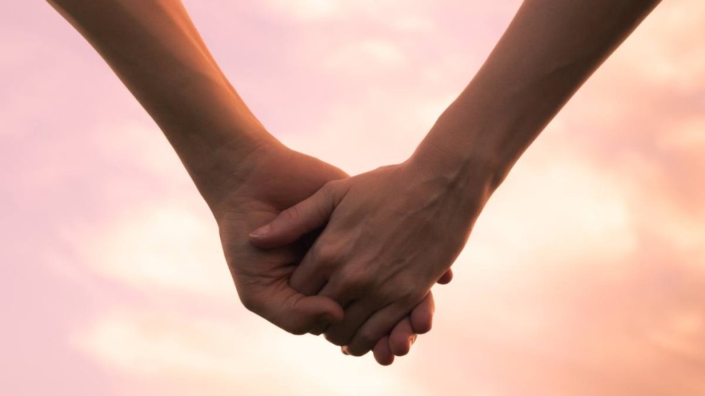 All about Gemini: Couple holding hands against the sunset.