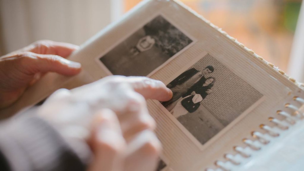 Gifts for Mother's Day: Close up view of a grandmother sharing memories and stories with her granddaughter while showing her an old family photo album. Memories and family concept.
