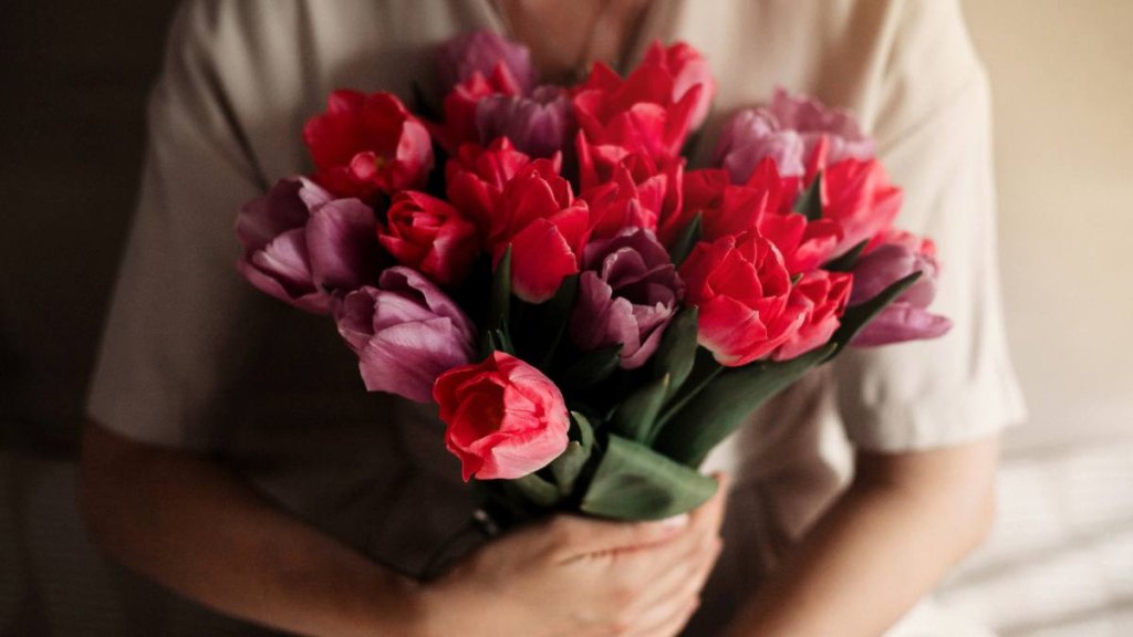 Top view of beautiful woman with bouquet of spring flowers at home bedroom